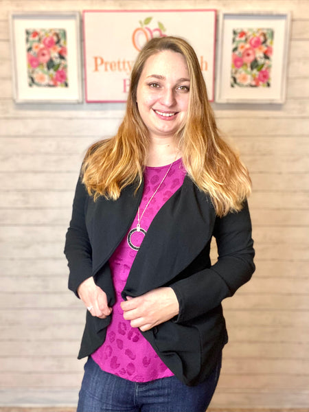 Model wearing our black open blazer. The blazer has a flattering cut that rounds out. Model pairs this blazer with our magenta leopard top and dark denim.