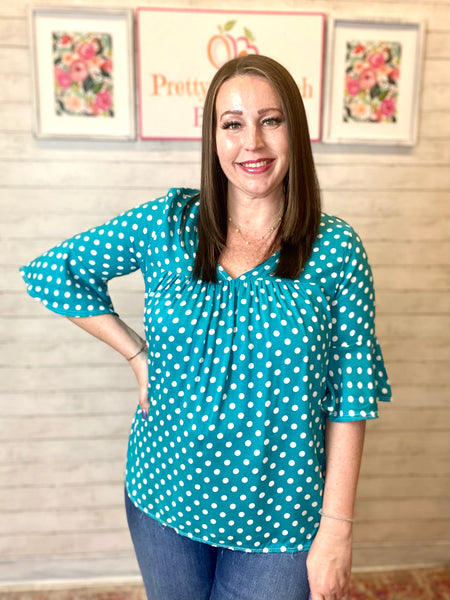 Model wearing our Jade Polka Dot Ruffle Sleeve Top. The top is 3/4 quarter sleeve with a wide bell effect. There is a v neckline and polka dot patterns. 