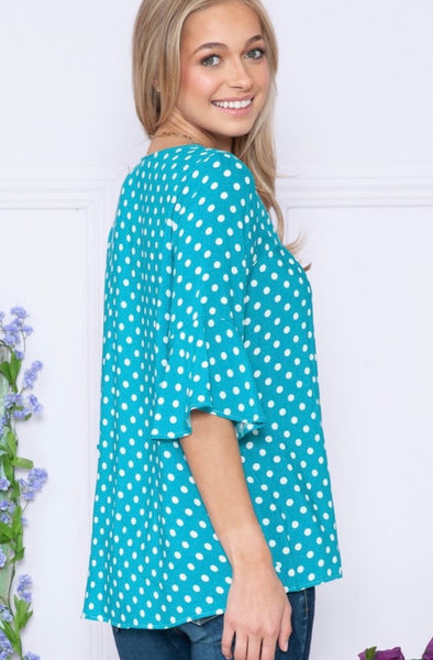 Model wearing our Jade Polka Dot Ruffle Sleeve Top. The top is 3/4 quarter sleeve with a wide bell effect. There is a v neckline and polka dot patterns.