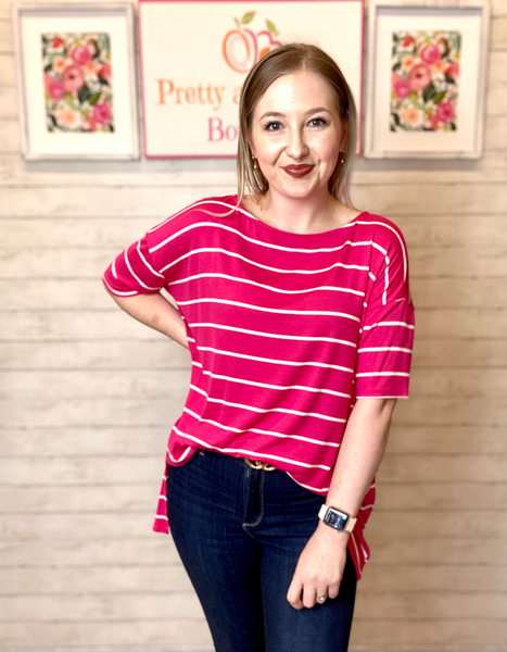 Model wearing our Fuchsia Oversized Striped Tunic. The top is elbow length and oversized. The top is fuchsia with white stripes horizontally. 