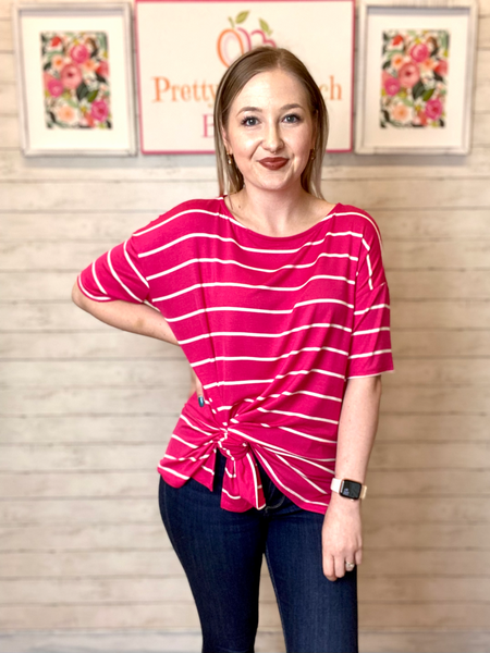 Model wearing our Fuchsia Oversized Striped Tunic. The top is elbow length and oversized. The top is fuchsia with white stripes horizontally. Model wearing our Fuchsia Oversized Striped Tunic. The top is elbow length and oversized. The top is fuchsia with white stripes horizontally. Model ties the bottom of the top for a fun look.