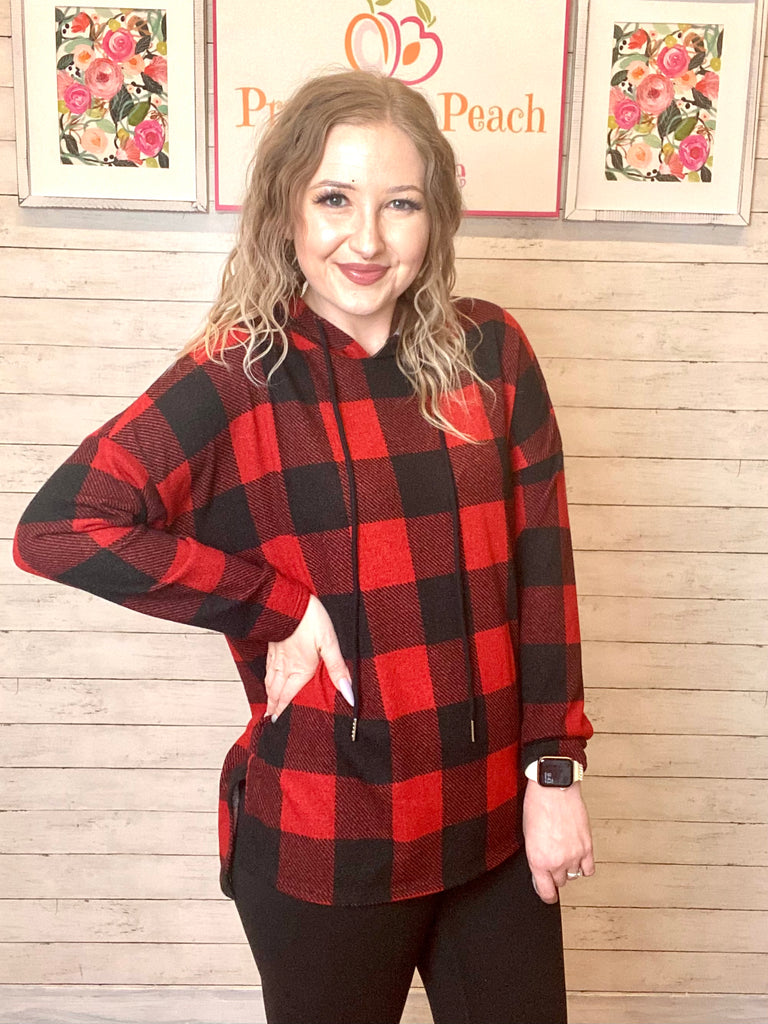 Model wearing our Black & Red Buffalo Plaid Hoodie. Hoodie has a small slit on either side at the bottom and black ties. The sweatshirt is legging friendly.