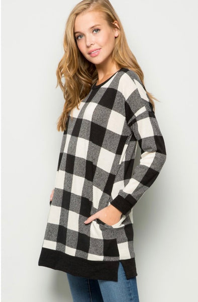 Model wearing our Black & Ivory Buffalo Plaid Tunic Sweater. The sweater is long sleeved, with pockets, and legging friendly. Model pairs the tunic sweater with light wash skinny jeans.