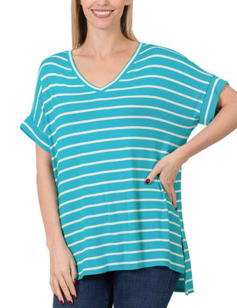 Model wearing our Deal of the Day Blue Striped Top. The top is short sleeve and is blue with white stripes. The top has a v neckline, folded sleeves, and a split on the sides with the top longer in the back than the front.