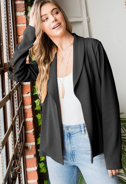 Model wearing our black open blazer. The blazer has a flattering cut that rounds out. Model pairs this blazer with light wash jeans, white tank top, and gold jewelry.
